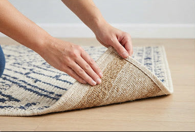 Applying EZ No Slip anti-slip coating to the backing of an area rug by flipping the rug over to expose the underside.